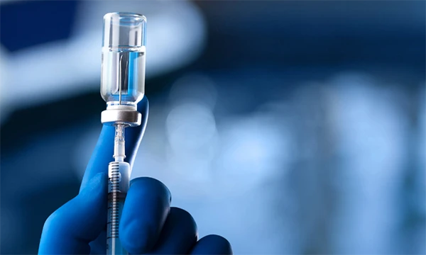 Healthcare workers extracting vaccine with a needle