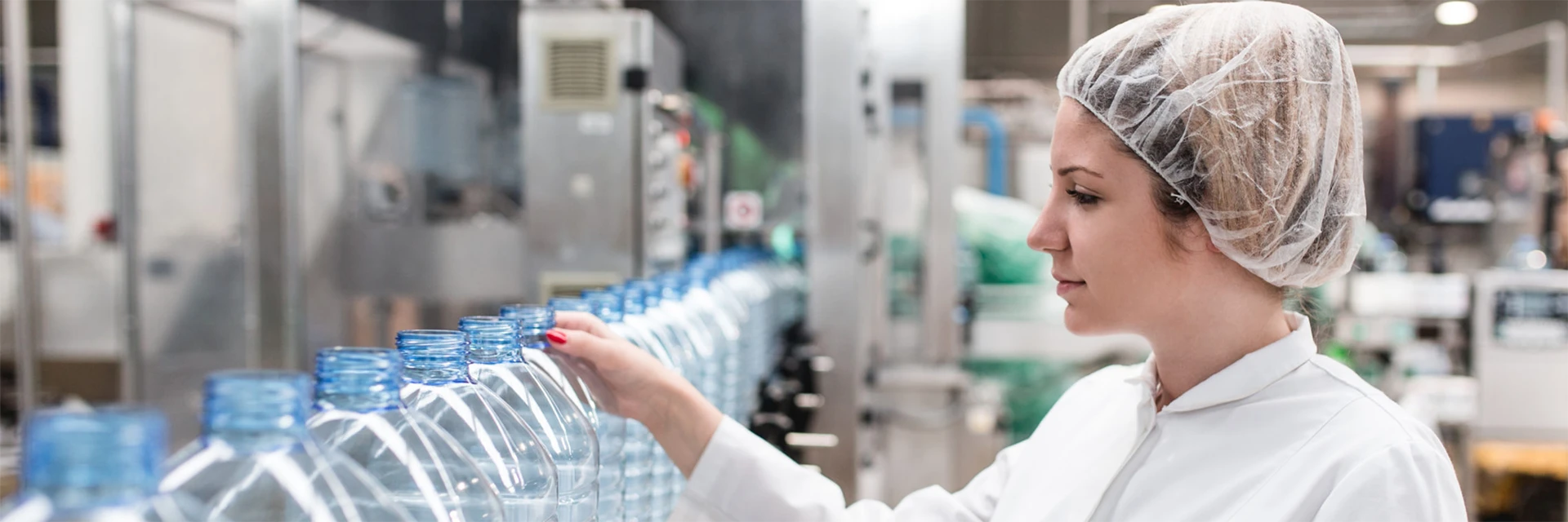 Female employee inspecting bottled water production line