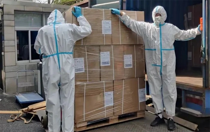 Workers wearing protective clothing are loading and delivering goods